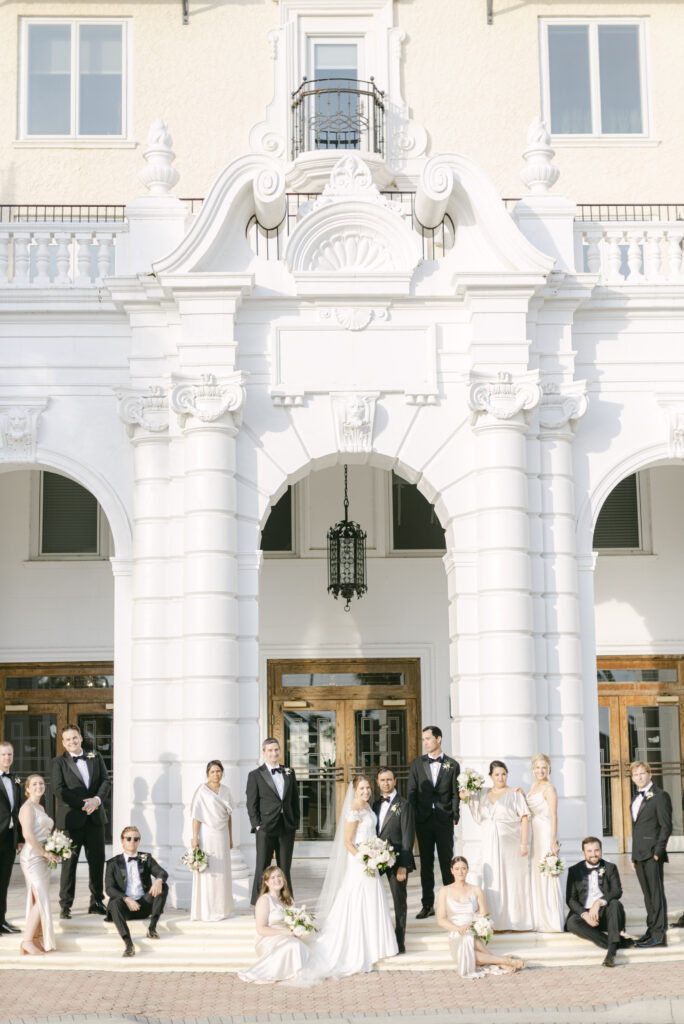Bride and Groom stand in front of two large columns surrounded by the wedding party.