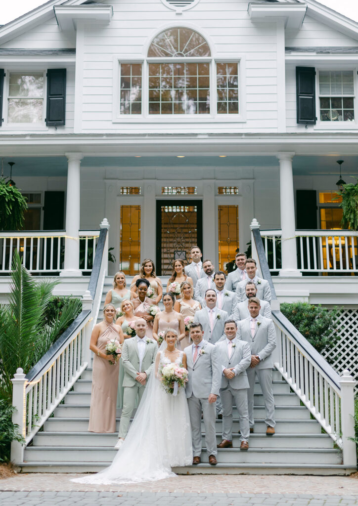Bride and Groom standing in front of wedding party at the bottom of the steps at the Mackey House
