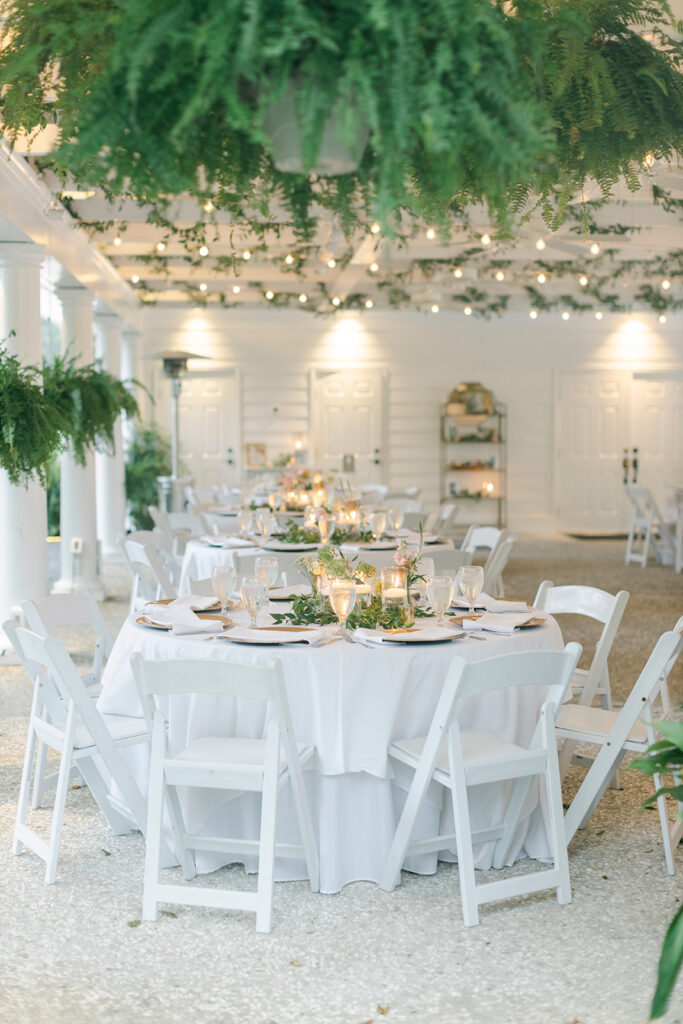 White tables and chairs with greenery around them set at the Mackey House.