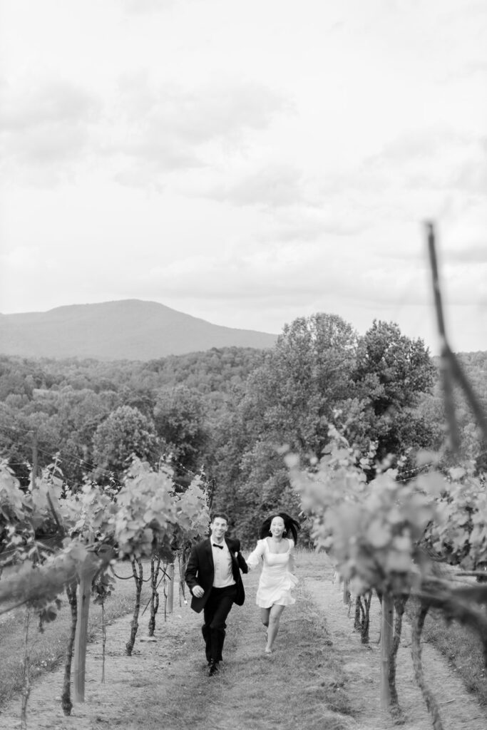 Man and woman playfully run through vineyard.