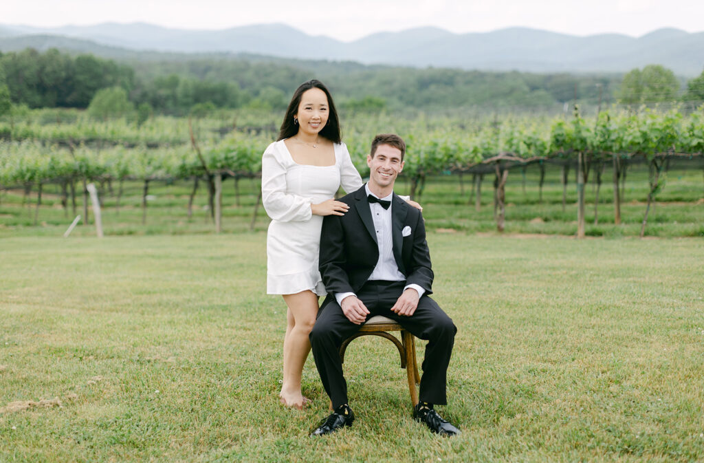 Couple seated in chair smiling in vineyard.