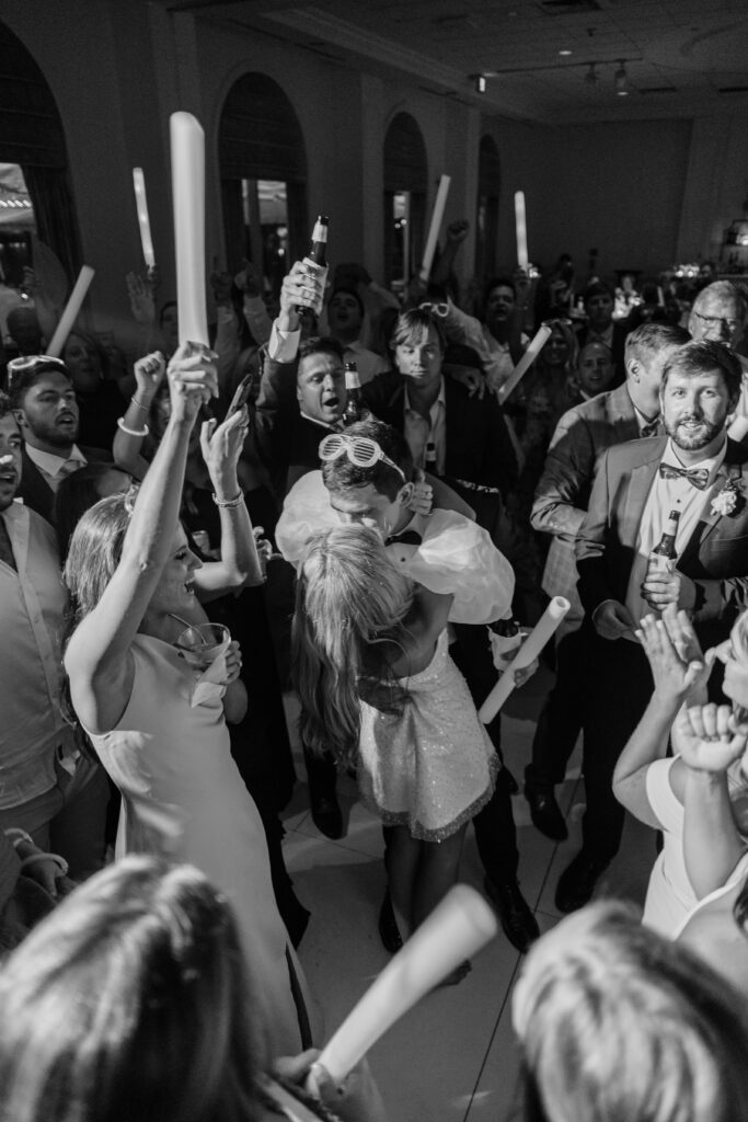 A bride and groom kiss in the middle of a dance floor. 