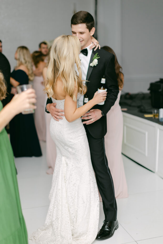A bride and groom dance while holding drinks. 