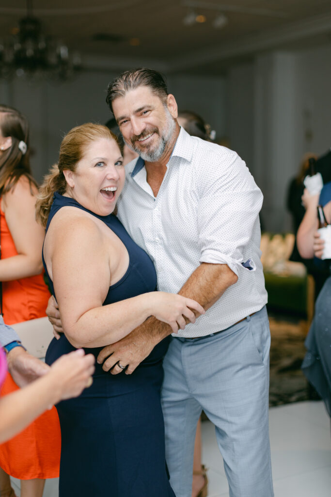 Two wedding guests laugh and hold one another. 