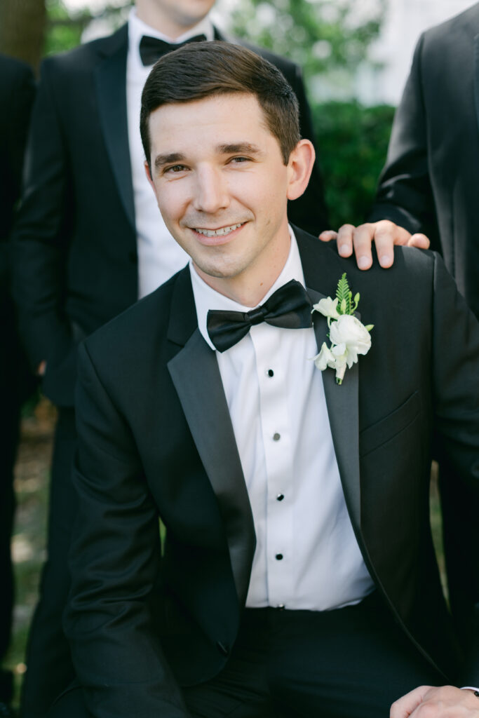 A groom seated with his groomsmen's hand on his shoulder. 