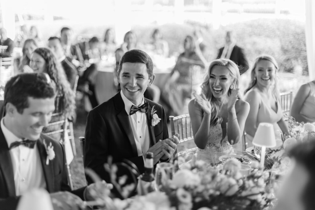 A bride and groom laugh while seated. 