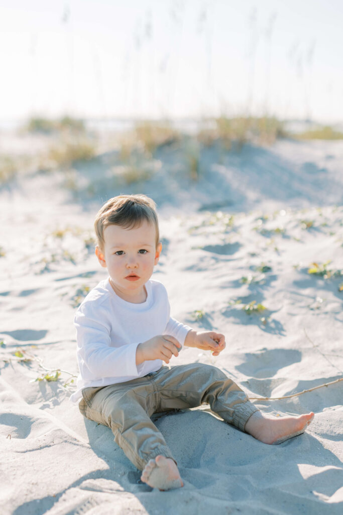 A little boy playing the sand at a maternity session. 