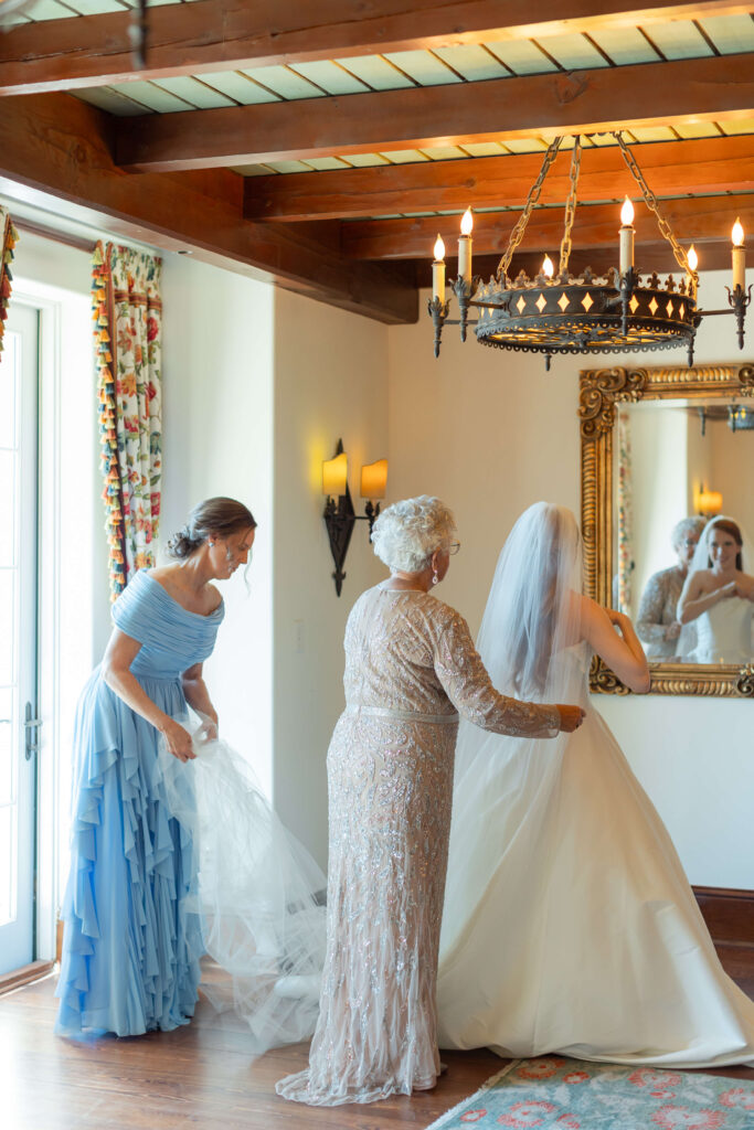 A grandmother helps a bride put on her veil. 
