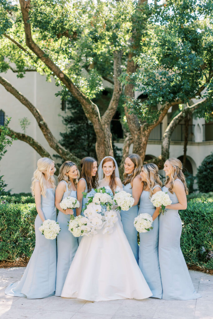 A bride and bridesmaids laugh with one another. 