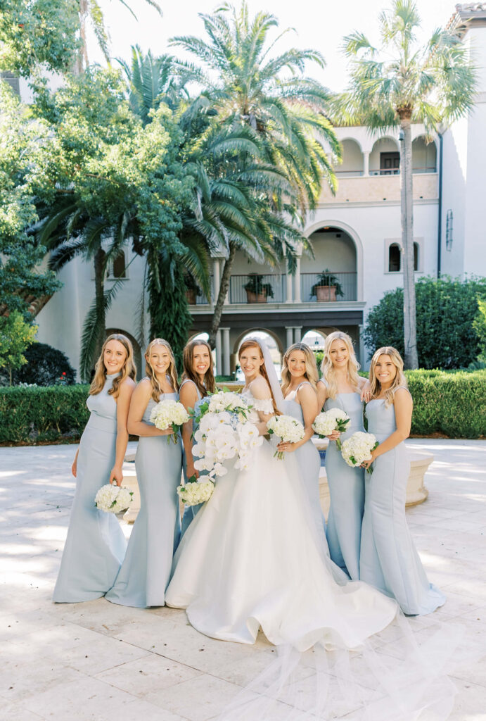 A bride and bridesmaids all smile while standing in the courtyard at the Cloister at Sea Island. 