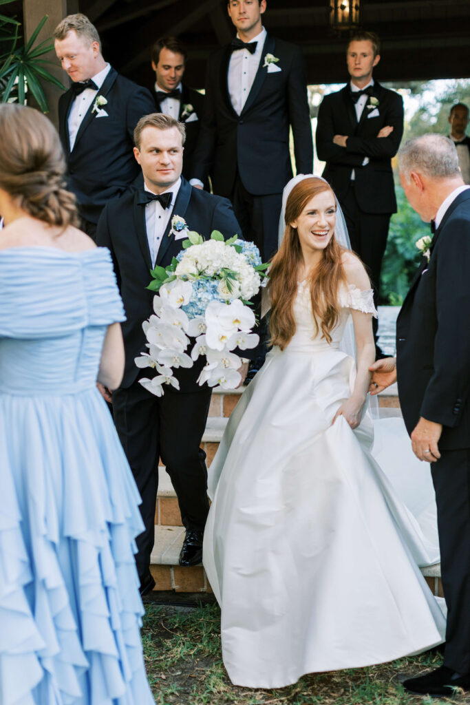 A bride smiles while walking with her new husband. 