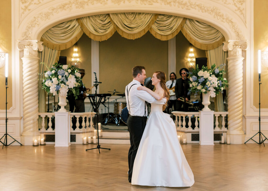 A bride and groom dance while back dropped by a stage of musicians. 