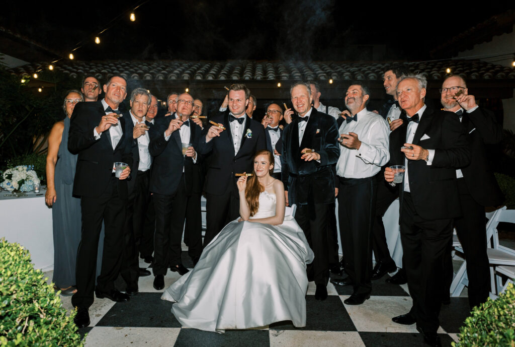A bride, groom and the men of the wedding all enjoy cigars. 