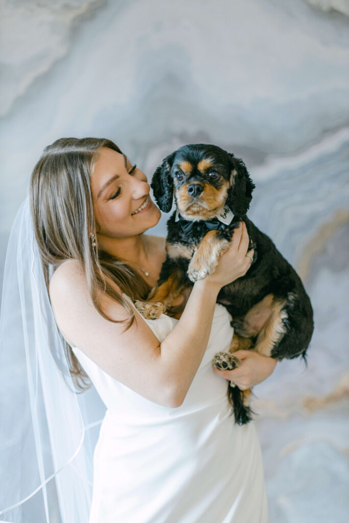 A bride holds a puppy. 