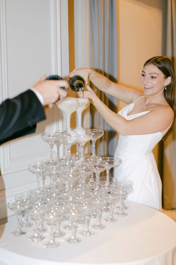 A bride and groom do a champagne tower. 
